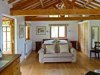 A bedroom with wooden beams a sofa bed a wooden floor and a wardrobe at The Springs in Ashey near Brading and Ryde