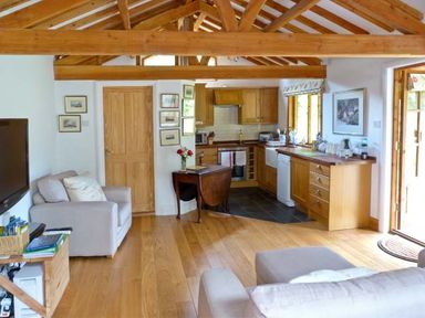 A living room and kitchen area with wooden beams and furniture at The Springs in Ashey near Brading and Ryde