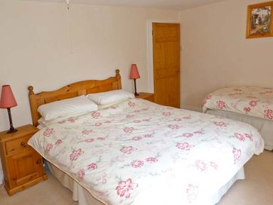 A bedroom with two beds wooden headboards bedside tables and lamps at High Kiln Bank Cottage in Seathwaite Duddon Valley