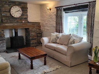 A living room with a stone fireplace a wooden coffee table and a sofa with rabbit cushions at High Kiln Bank Cottage in Seathwaite Duddon Valley