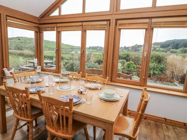 A dining room with a wooden table set for a meal at Lough Cluhir Cottage in Union Hall, County Cork