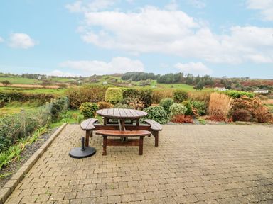 A garden with a picnic table and benches at Lough Cluhir Cottage in Union Hall, County Cork