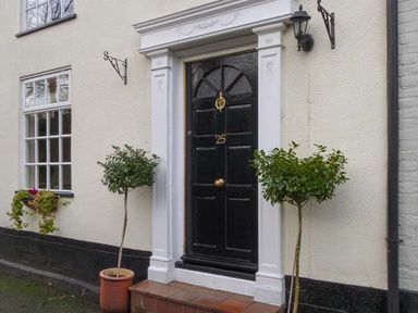 A black front door with the number 25 and two potted small trees on either side at Teds Place in Aylsham