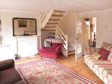 A living room with armchairs a sofa a patterned rug and a staircase at Teds Place in Aylsham
