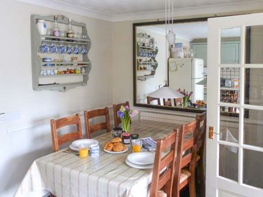 A dining table with chairs cups plates croissants orange juice and flowers on a table at Teds Place in Aylsham