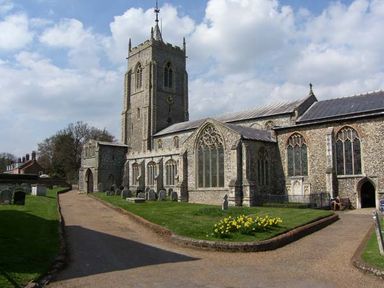 A stone church with a tall tower and arched windows surrounded by a pathway and grass with gravestones