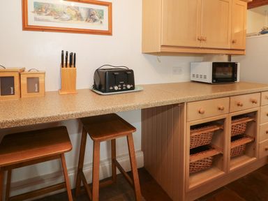 A kitchen countertop with a toaster knife block containers stools and microwave at Blencathra Barn in Penrith