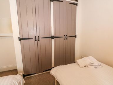 A bedroom with two beds a set of double closet doors and folded towels on a bed at Blencathra Barn Penrith