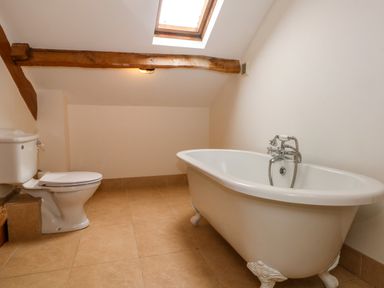 A bathroom with a clawfoot bathtub a toilet and a skylight at Blencathra Barn in Penrith