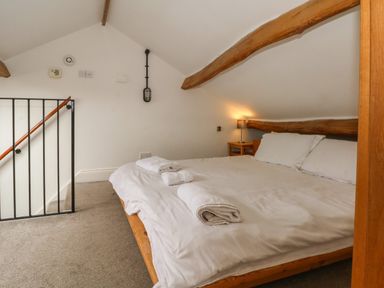 A bedroom with a double bed towels on the bed and a bedside table with a lamp at Blencathra Barn in Penrith