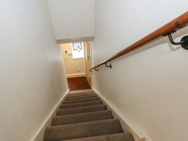 A carpeted staircase with wooden handrail and white walls at Blencathra Barn in Penrith