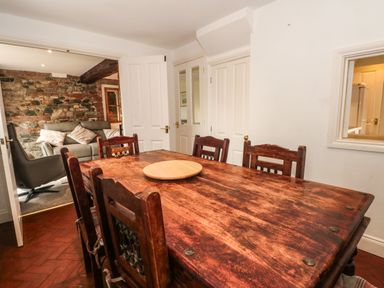 A wooden dining table with chairs in a room with white walls and doors at Saddleback Barn in Newton Reigny near Penrith