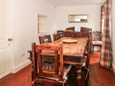 A dining room with a wooden table and chairs and a mirror on the wall at Saddleback Barn in Newton Reigny near Penrith