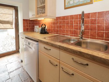 A kitchen counter with a sink dishwasher kettle and cabinets at Saddleback Barn in Newton Reigny near Penrith