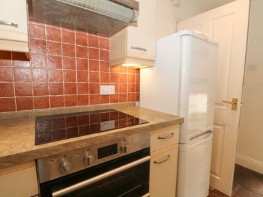 A kitchen with stovetop oven fridge and red tiled backsplash at Saddleback Barn in Newton Reigny near Penrith