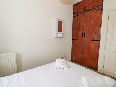 A bedroom with a bed with white towels on it a wooden wardrobe and a small wall cabinet at Saddleback Barn in Newton Reigny near Penrith