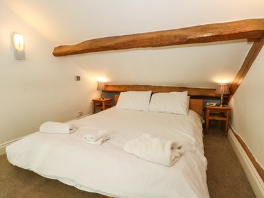 A bedroom with a bed and two bedside tables with lamps at Saddleback Barn in Newton Reigny near Penrith
