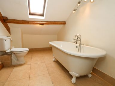 A bathroom with a clawfoot bathtub a toilet and a skylight at Saddleback Barn in Newton Reigny near Penrith