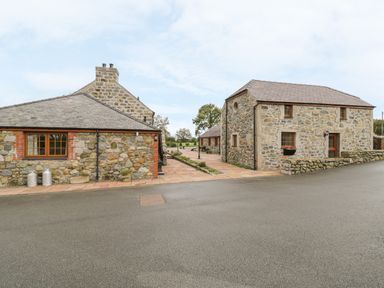 Stone cottages with tiled roofs and paved walkways at Lily Cottage in Caeathro near Caernarfon