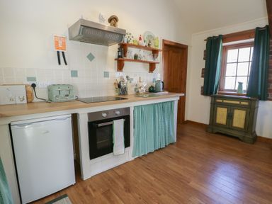 A kitchen with appliances and wooden furniture at Lily Cottage Caeathro near Caernarfon