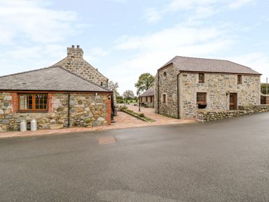 Stone houses with tiled roofs and paved walkway between them at Lavender Cottage in Caeathro near Caernarfon