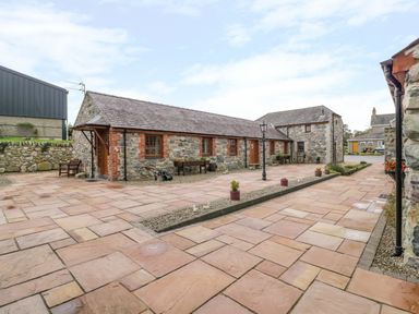 A stone courtyard with benches lamp posts and potted plants at Lavender Cottage in Caeathro near Caernarfon