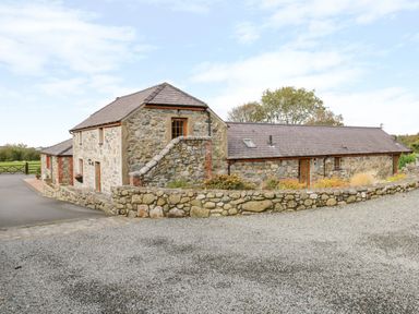 Stone house with wooden framed windows and gravel driveway at Lavender Cottage in Caeathro near Caernarfon