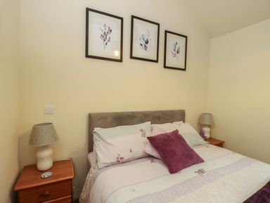 A bedroom with a bed and lamps at Lavender Cottage in Caeathro near Caernarfon
