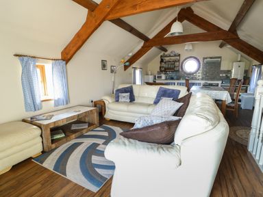 A living room with a sofa and table at Bluebell Cottage in Caeathro near Caernarfon