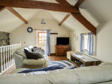 A living room with a sofa and television at Bluebell Cottage in Caeathro near Caernarfon