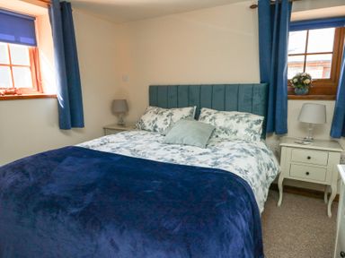 A bedroom with a bed and bedside table at Bluebell Cottage in Caeathro near Caernarfon
