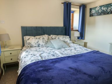 A bedroom with a bed and bedside tables at Bluebell Cottage Caeathro near Caernarfon