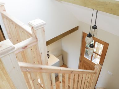 A wooden staircase with banisters leading to a wooden front door with glass panels at Bicton Lodge in Clun