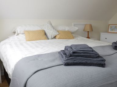 A bed with pillows towels and a lamp on a side table at Bicton Lodge in Clun