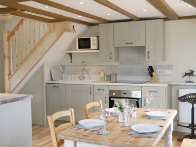 A kitchen and dining area with wooden table set with plates and glasses at Bicton Lodge in Clun