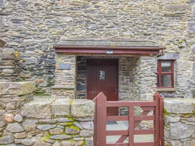 Entrance to a stone barn with a wooden door and gate at Hill Side Barn in Pennington near Ulverston
