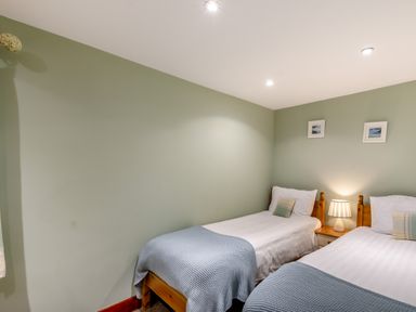 A bedroom with two single beds a wooden nightstand and a lamp at Hill Side Barn Pennington near Ulverston
