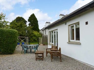 An outdoor patio area with wooden chairs and table and plastic chairs around a round table at The Range in Enniscorthy County Wexford