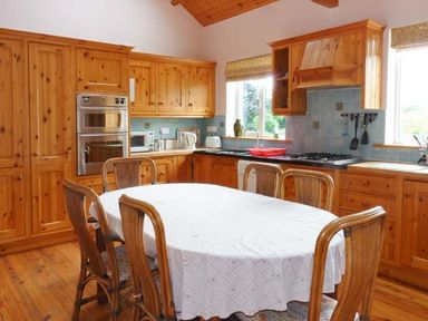 A kitchen with wooden cabinets dining table with white tablecloth and wooden chairs at The Range in Enniscorthy County Wexford