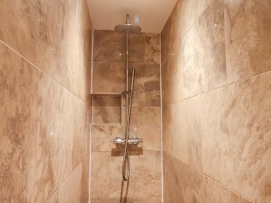 A shower with a showerhead and wall tiles at The Lodge in Snainton near Scarborough