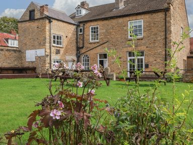 A garden with flowers and a building in the background at The Lodge in Snainton near Scarborough