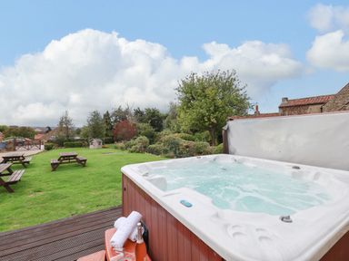 A garden with a hot tub and picnic tables at The Lodge in Snainton near Scarborough