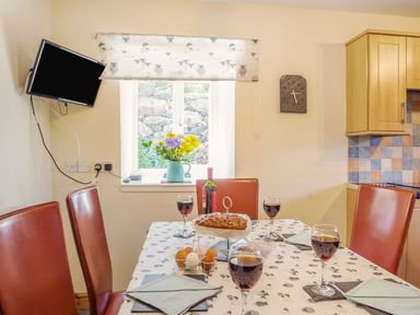 A dining table with wine glasses bottles eggs and cake in a kitchen at Ty Nant in Betws-y-Coed