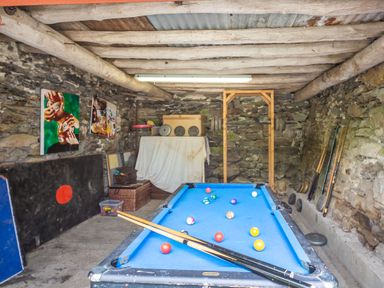A game room with a pool table and weightlifting equipment in a stone wall basement at Ty Nant in Betws-y-Coed