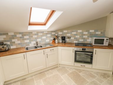 A kitchen with a double sink a toaster a knife block a coffee maker a microwave and an oven at Foxglove Cottage in Little Haven near Haverfordwest