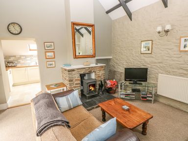 A living room with a wood burning stove a sofa and a wooden coffee table at Foxglove Cottage in Little Haven near Haverfordwest