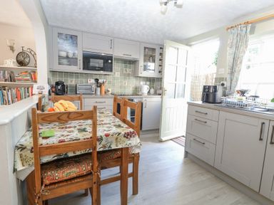 A kitchen with wooden chairs around a table and grey cabinets at Peggotty's in Kelsale near Saxmundham