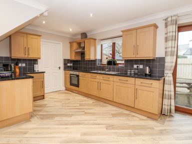 A kitchen with wooden cabinets black countertops and a window at Bryn Seion in Y Felinheli