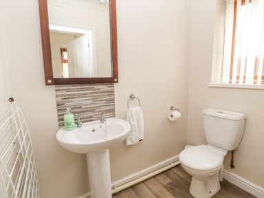 A bathroom with a pedestal sink mirror toilet towel and a window at Bryn Seion in Y Felinheli