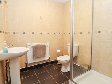 A bathroom with a sink a toilet a glass shower enclosure and a towel on a radiator at Bryn Seion in Y Felinheli